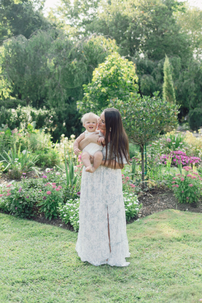 standing in garden mom holding baby and looking at baby smiling